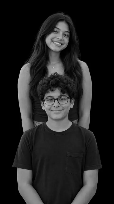 The same brother and sister as a stacked monochrome studio portrait on a black background, the taller girl at the back and the boy in front